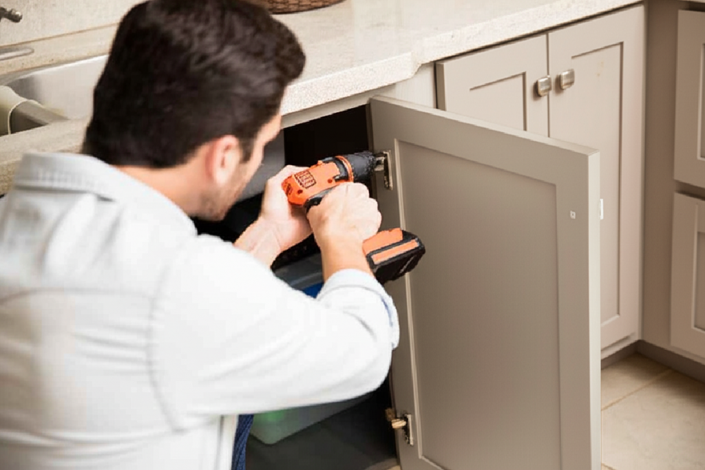 Person installing cabinet doors with a screw gun.